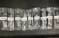 Nine individually packaged black cabinet pull handles arranged in a row, showing packaging and condition as new.