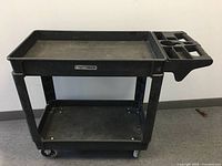 Full view of black MotoMaster service cart showing two trays and the handle attachment with compartments.