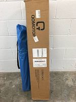 Two carrying bags side by side: larger lime green bag with QOMOTOP branding containing the tent and smaller blue bag containing the folding chair.