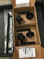 Two Ridgecrest flat black lever door handles disassembled and boxed, with parts and instructions visible.