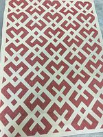 Top view of the outdoor rug showing red and cream geometric pattern with interlocking shapes.