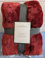Front view of folded dark red micro plush blanket with grey strap and Threshold label showing product details.