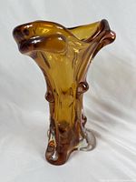 Front and side view of amber glass vase shaped like a tree trunk with organic textured surface and upward flaring top.