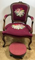 Front view of antique needlepoint parlour chair and matching foot stool. Chair has floral needlepoint on backrest and seat, carved wood frame, maroon fabric upholstery. Stool covered with matching fabric.