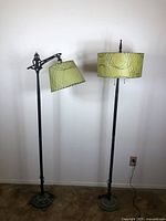 Full view of both antique/vintage metal floor lamps side-by-side showing bases, poles, and lampshades with green abstract swirl pattern.