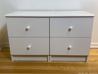 Front view of two white bedside tables with four drawers total, showing round knobs on each drawer and consistent surface wear.