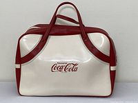 Full front view of Coca-Cola white and red duffle bag with handles, showing logo and overall bag condition.