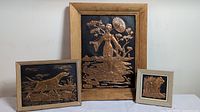 Full view showing three framed copper art pieces: large central with woman and parasol, medium with dog, small square with foliage.