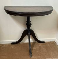 Front view of the half moon table showing pedestal and brass claw feet.