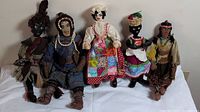 Front view of all six handmade dolls sitting side by side showing varied fabrics, colors, and styles.