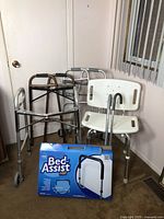 Full view of all items including bath chair, two canes, three walkers, and boxed bed assist rail.