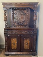 Full frontal view of the Jacobean style wood cabinet showing ornate central door with emblem and turned columns.