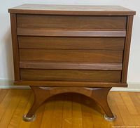 Front view showing three drawers, integrated wood handles and sculpted curved arch base
