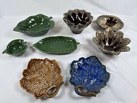 Top view of all ceramic items in the lot arranged on white surface, showcasing various leaf-shaped bowls and plates in green, brown, and blue colors.