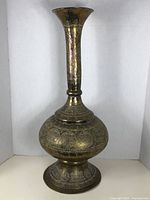 Full view of the tall brass vase showing flared neck and bulbous body with etched Islamic designs.