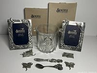 Photo of two Seagull pewter picture frames, glass ice bucket with embossed grapevine design, and various pewter accessories including a letter opener, small spoon and 4 decorative pins or clips. All items show wear consistent with age and use.