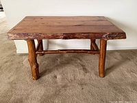 Front view of handmade pine coffee table showing thick legs and solid plank top with natural wood edges.