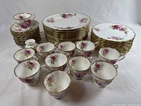 Overview of all dinnerware pieces: dinner plates, luncheon plates, teacups and saucers arranged on table.