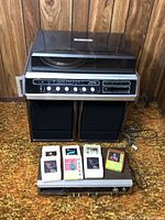 Full view of Toshiba stereo system, speakers, 8-track player and 8-track tapes on carpeted floor