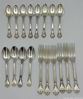 Top-down view showing eight spoons on top row and four spoons plus six forks on bottom row.