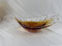 Side angle view of the glass leaf bowl showing the curved lip and orange to clear gradient coloration.