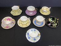 Full display of nine assorted teacup and saucer sets on black backdrop