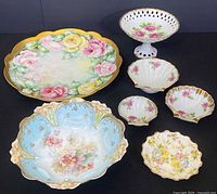 Overview of full set including large floral Limoges platter, white pedestal dish, three matching shell dishes, and blue bowl.