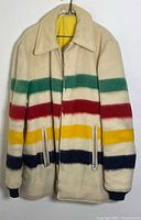 Front view of cream off-white wool coat with multicolor stripes on body, ring-pull front zipper, side zippered pockets and knit cuffs