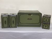 Full set of five olive green metal vintage kitchen containers including bread box and four canisters labeled Sugar, Flour, Tea, Coffee with chrome lids.
