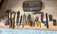 Overview photo showing all vintage tools and metal toolbox arranged on wooden surface.