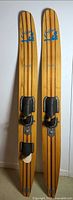 Full view of both wooden water skis showing bindings and stripe design
