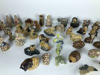 Wide assortment of Wade Whimsies Red Rose Tea miniature ceramic animal and character figurines arranged on a white surface under bright light.