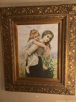 Frontal view of main framed art showing woman carrying child and ornate gold frame.