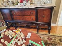 Front view of buffet with decorative items on top and table with figurines in foreground