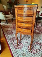 Front view showing four drawers, brass knobs, inlaid veneer and glass top