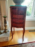 Front view of wooden cabinet showing four drawers, glass top and cabriole legs