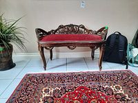 Front view showing full bench, carved frame and upholstered seat