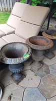 Two cast iron urn planters displayed on patio