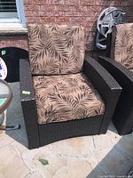Front view of the outdoor patio chair showing the seat and backrest cushions and faux wicker frame.