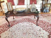 Full front view of the mahogany coffee table showing carved legs and decorative edges.