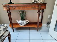 Full front view of wood console table with glass top, drawer closed, lower shelf and carved leg detailing