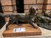 Front profile view showing the dog’s right side and wood base
