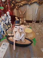View of skeleton couple figurine in canoe with salt and pepper shakers, wooden rabbit, teacups, and candle