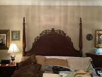 Front view of the mahogany four-poster bed with decorative headboard and bedding on top.