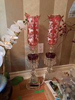 Pair of ruby glass crystal boudoir lamps on a surface, showing general height and design