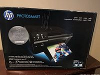 Front view of HP Photosmart printer original box showing product image and main features including print, scan, copy, web printing, and wireless capabilities.