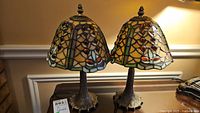 Front view of both stained glass lamps on table showing shades and bases