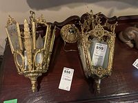 Two vintage metal hanging lamps on a dark wood surface, detailed view of metalwork and etched glass panels.