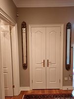 Pair of matching wall mirrors mounted on either side of a double door, showing full length and placement in room.