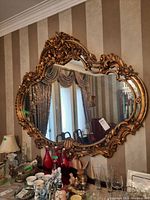 Front view of the large ornate gold framed mirror showing detailed surrounding room reflection